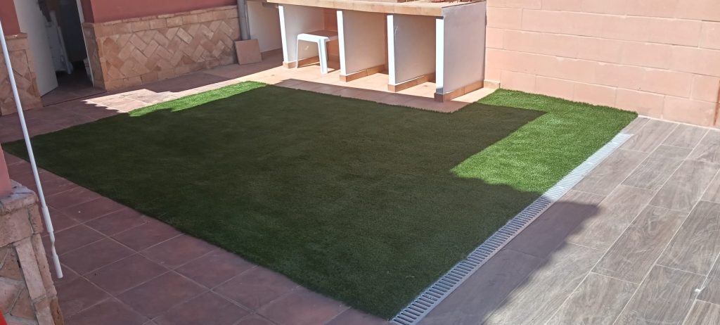 Instalación de césped artificial terminada junto a cocina exterior - Limcesped Sevilla